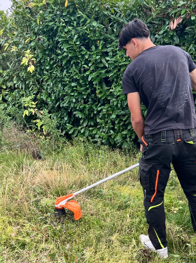 GlanzWerk Service Mitarbeiter beim Rasenmähen mit Freischneider