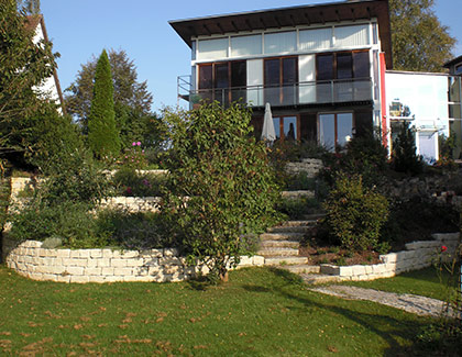Nachher: terrassierter Hanggarten mit Natursteinmauern, Treppenanlage und Bepflanzung